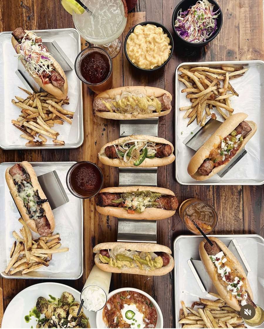Overhead spread of house-made brats, dogs and sides at Wurst Behavior Chicago